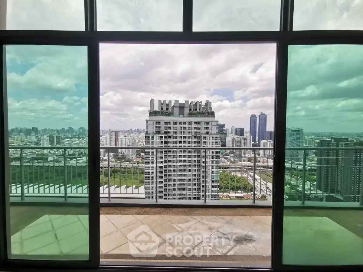 Stunning cityscape view from a high-rise balcony with glass doors, perfect for urban living.
