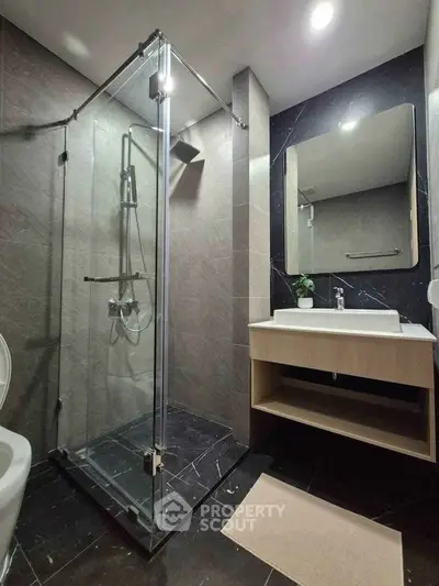 Modern bathroom with glass shower and sleek vanity in luxury apartment.