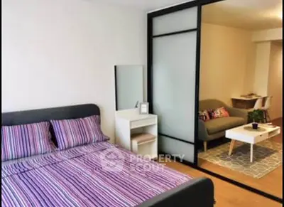 Modern bedroom with sliding glass partition and cozy living area, perfect for urban living.