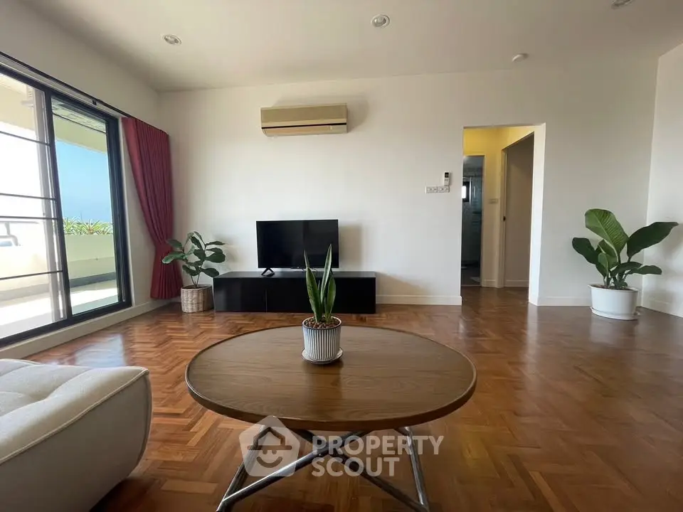 Spacious living room with parquet flooring and balcony access