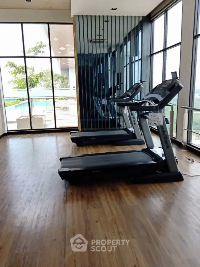 Modern gym with treadmills and large windows offering scenic views.