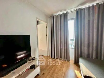 Bright living room with modern TV setup and large window with curtains.