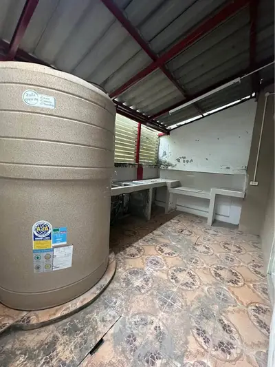 Spacious outdoor utility area with large water tank and tiled flooring, perfect for storage or laundry setup.