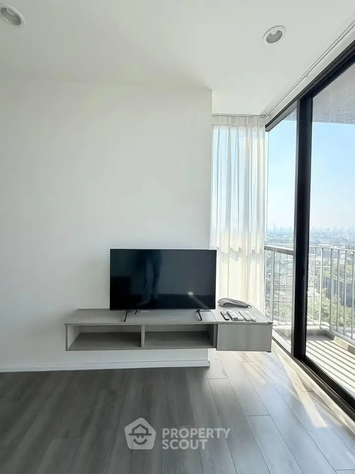 Modern living room with sleek TV setup and stunning city view from large balcony.