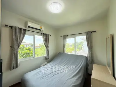 Cozy bedroom with natural light and garden view, featuring air conditioning and elegant curtains.