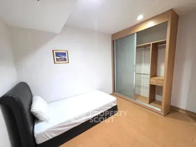 Cozy minimalist bedroom with single bed and built-in wardrobe, perfect for urban living.