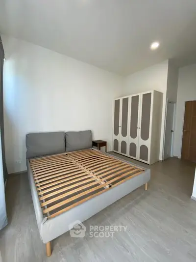 Spacious bedroom with modern bed frame and wardrobe, perfect for a cozy retreat.