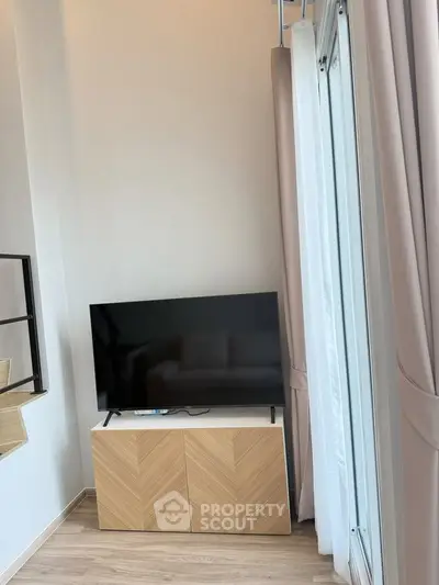 Modern living room with sleek TV stand and large windows for natural light.