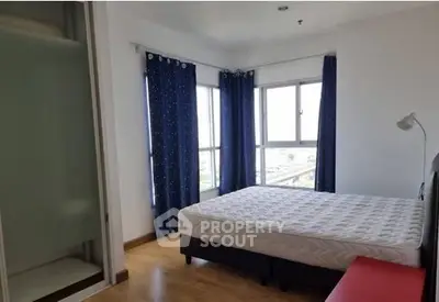 Bright bedroom with large windows and blue curtains in modern apartment.