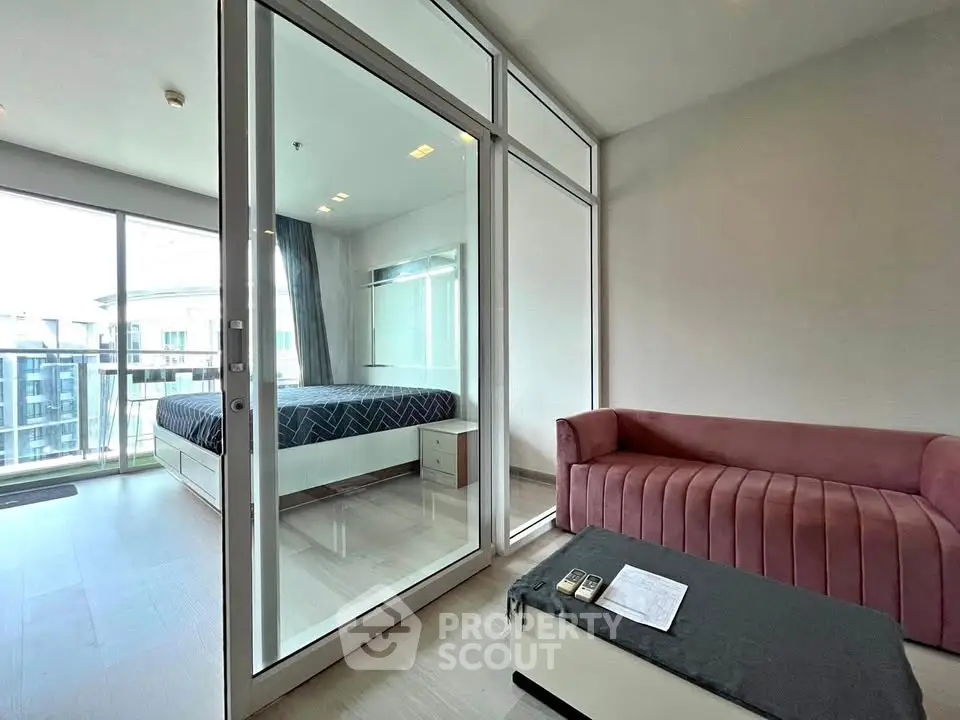 Modern apartment with glass partition, cozy living area, and bright bedroom view.