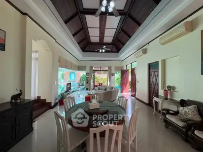 Spacious living room with high ceilings and elegant decor, featuring a dining area and large windows for natural light.