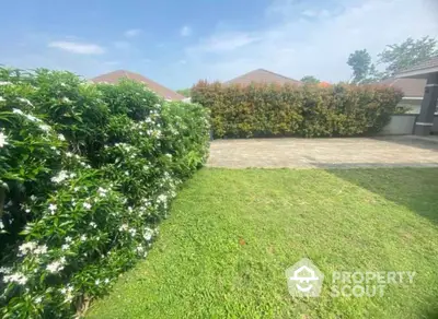 Spacious garden with lush greenery and paved area in a serene residential setting.