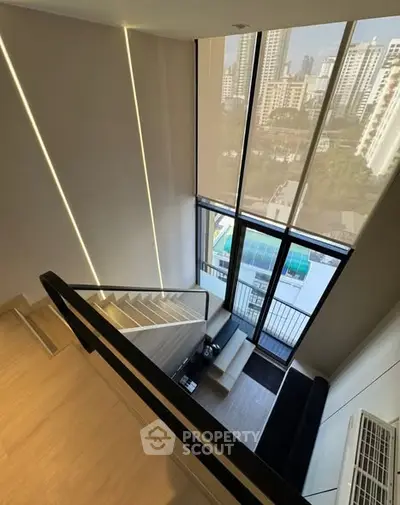 Stunning modern duplex with floor-to-ceiling windows and city views, featuring sleek staircase and elegant design.
