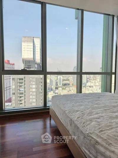 Luxurious bedroom with stunning city view through floor-to-ceiling windows.