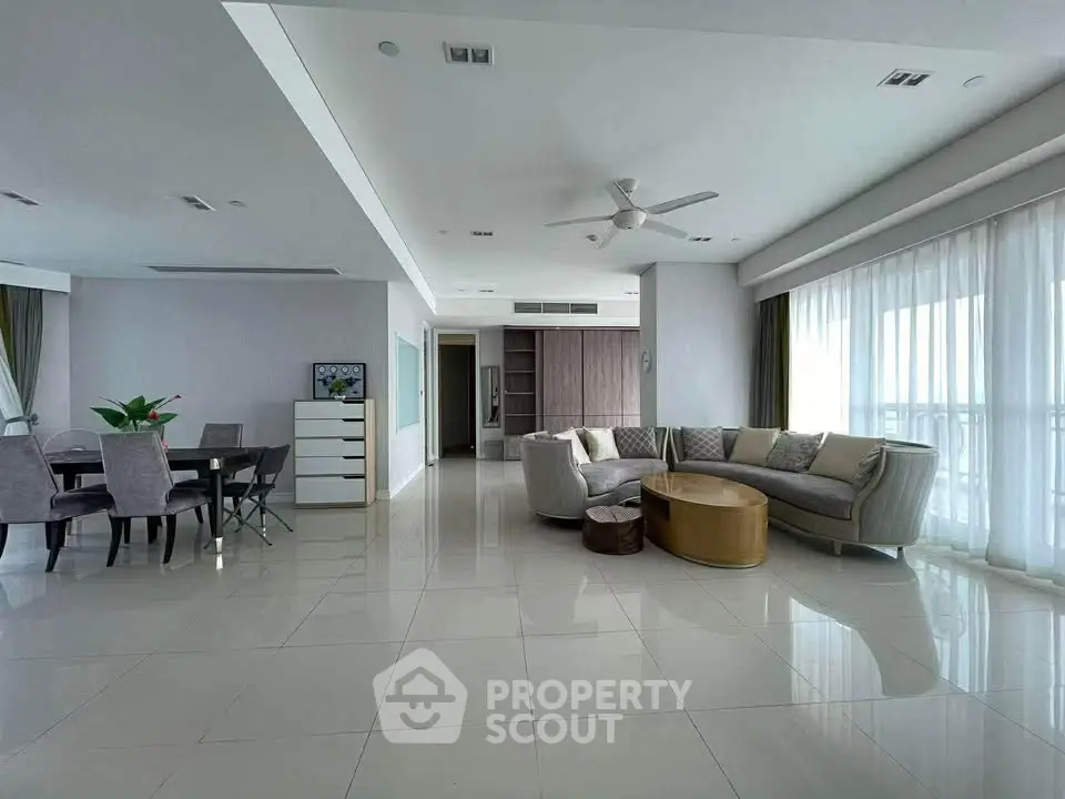 Spacious modern living room with elegant dining area and large windows offering natural light.