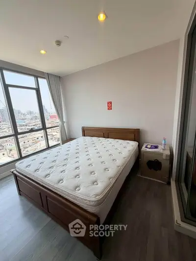 Spacious bedroom with city view, featuring a large window and modern furnishings.