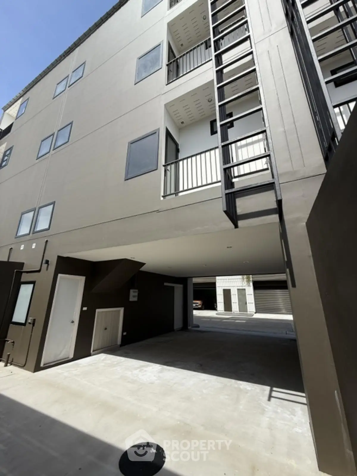 Modern apartment building exterior with sleek design and spacious parking area.