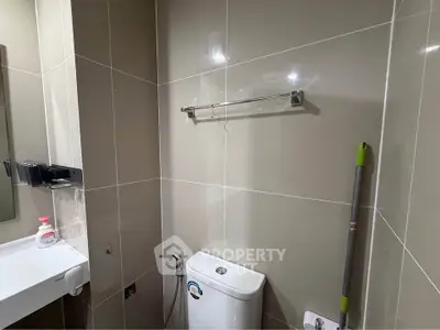 Compact bathroom with modern fixtures and tiled walls, featuring a toilet and sink.