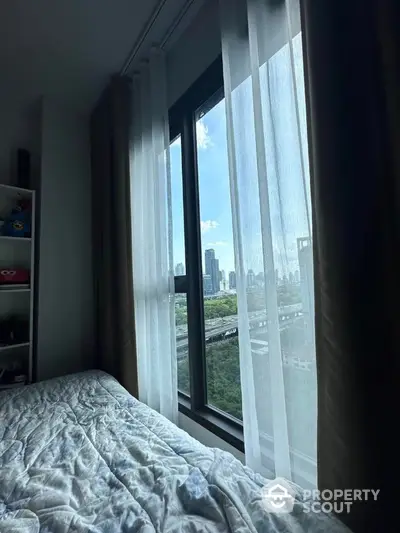 Cozy bedroom with stunning city view through large window and sheer curtains