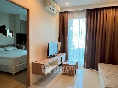 Modern apartment interior with cozy living room and adjacent bedroom, featuring stylish furniture and natural light.