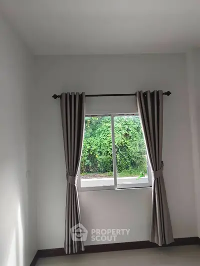 Bright room with window view of lush greenery, featuring elegant curtains and natural light.