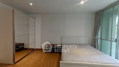 Spacious bedroom with large mirrored wardrobe and natural light from floor-to-ceiling windows.