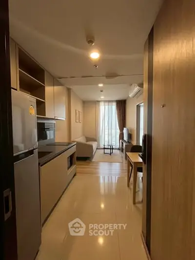 Modern apartment interior with open kitchen and cozy living area, featuring sleek appliances and stylish decor.