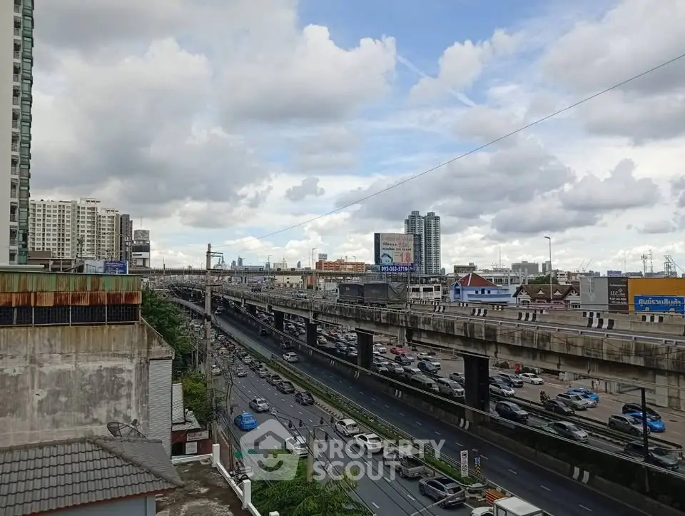Urban cityscape view with highway and residential buildings under a cloudy sky, showcasing vibrant city life.