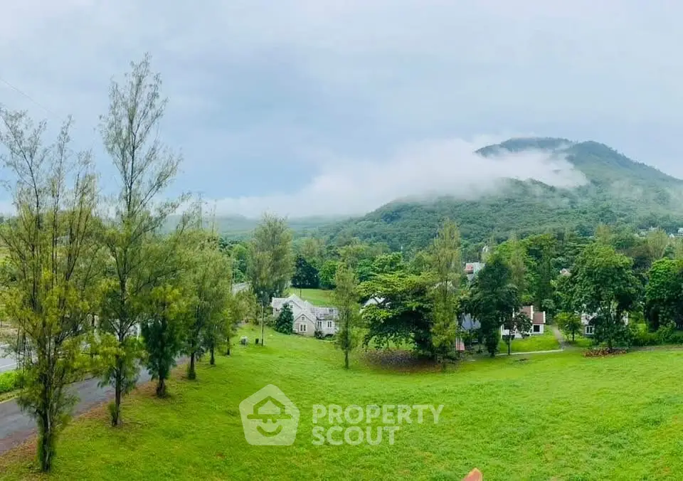 Scenic view of lush green landscape with houses and mountains in the background.