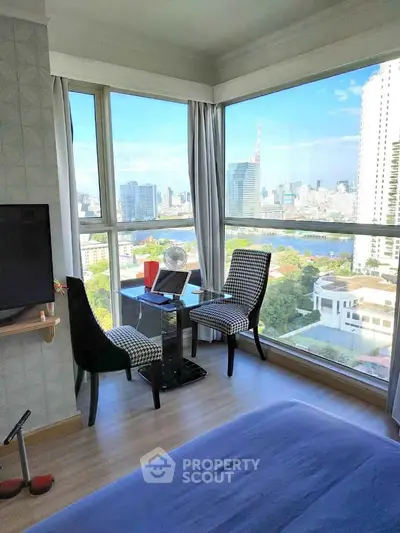 Stunning bedroom with panoramic city view and cozy seating area.