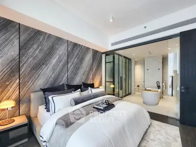 Luxurious modern bedroom with ensuite bathroom featuring a freestanding bathtub and elegant decor.
