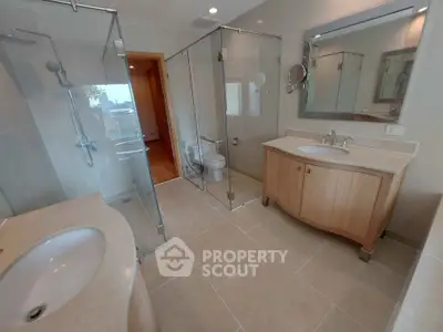 Spacious modern bathroom with dual sinks and glass shower enclosure