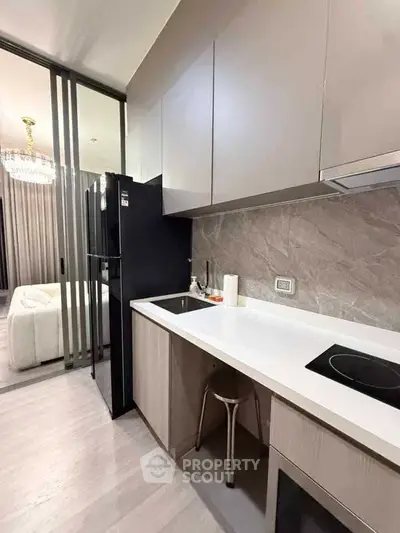 Modern kitchen with sleek cabinetry and induction cooktop, adjacent to a stylish living area.