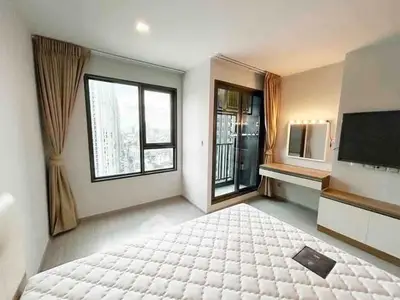 Modern bedroom with city view and balcony access in a high-rise apartment.