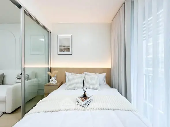 Modern bedroom with cozy decor and natural light, featuring a sliding glass door and stylish furnishings.