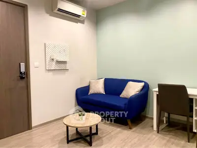 Modern living room with blue sofa, desk, and air conditioning in a cozy apartment.