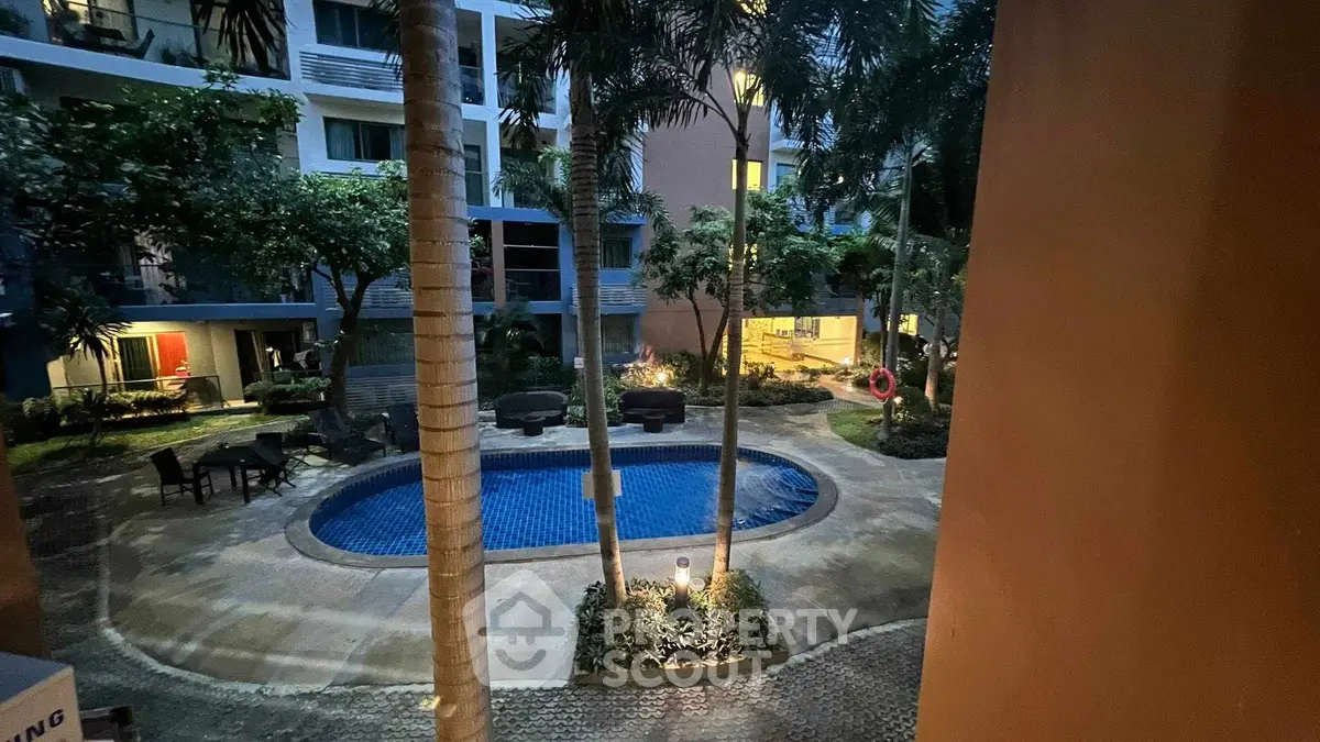 Charming residential pool area with lush greenery and cozy seating, perfect for relaxation.