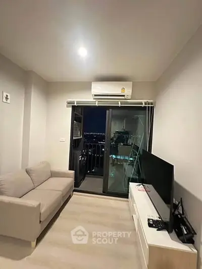 Modern living room with balcony view, featuring cozy sofa and sleek TV setup.