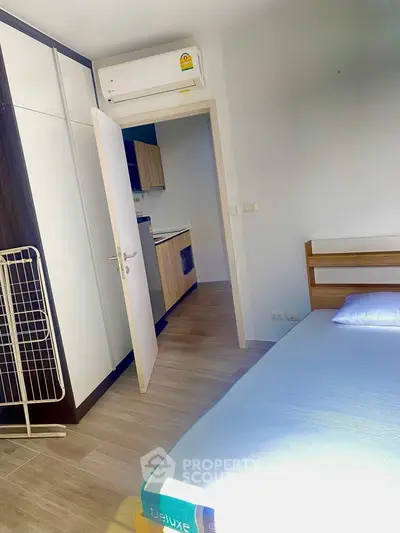 Modern bedroom with air conditioning and view into a stylish kitchen, perfect for urban living.