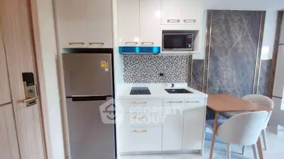 Modern kitchen with sleek appliances and stylish dining area in a contemporary apartment.