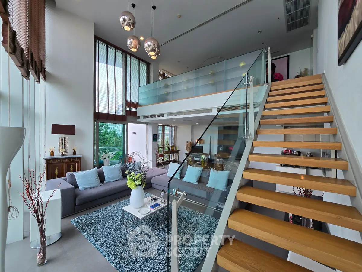 Luxurious modern living room with mezzanine, stylish decor, and elegant staircase in a spacious open-plan design.