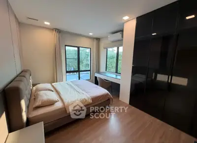 Spacious modern bedroom with large windows and sleek black wardrobe