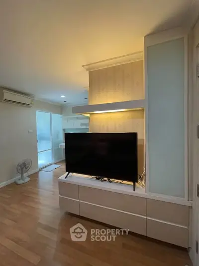 Modern living room with wooden flooring, TV unit, and air conditioning in a cozy apartment.