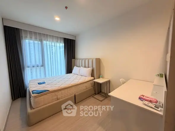 Modern bedroom with stylish bed, natural light, and sleek furnishings in a contemporary apartment.