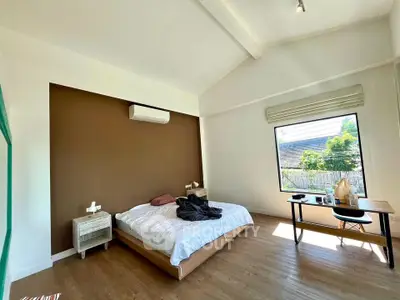 Spacious bedroom with large window and modern furnishings in a bright home.