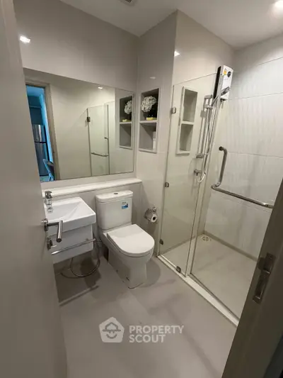 Modern bathroom with glass shower and sleek fixtures in contemporary apartment.