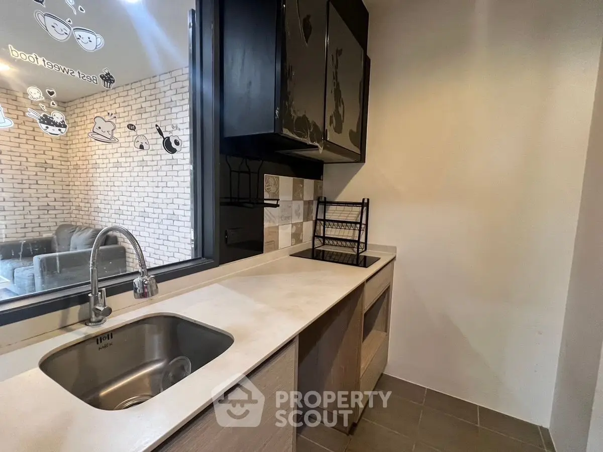 Modern kitchen with sleek cabinetry and stylish backsplash in a cozy apartment.