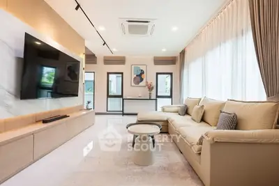 Spacious modern living room with large sofa and wall-mounted TV, featuring elegant decor and ample natural light.