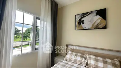 Cozy bedroom with modern decor and large window offering lush green views.