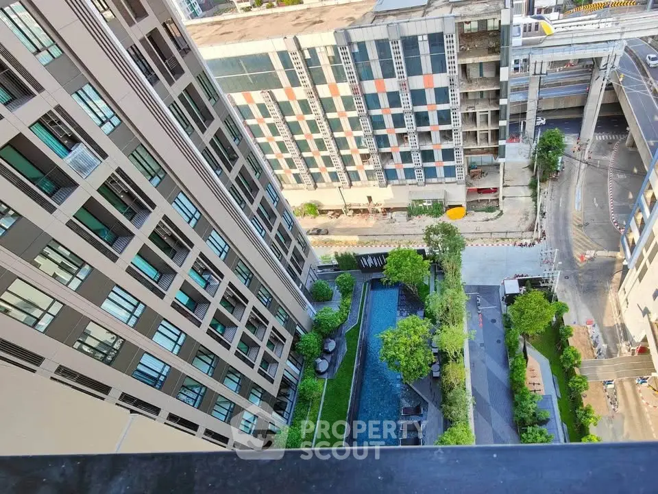 Stunning aerial view of modern apartment complex with lush garden and pool in urban setting.